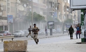A member of the Libyan army runs with a weapon during clashes between members of Islamist militant group Ansar al-Sharia and a Libyan army special forces unit in Ras Obeida