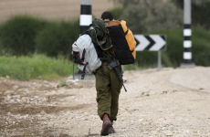 Israeli soldier carries bags to bus stop at Beeri