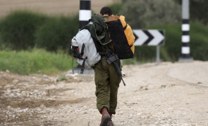 Israeli soldier carries bags to bus stop at Beeri